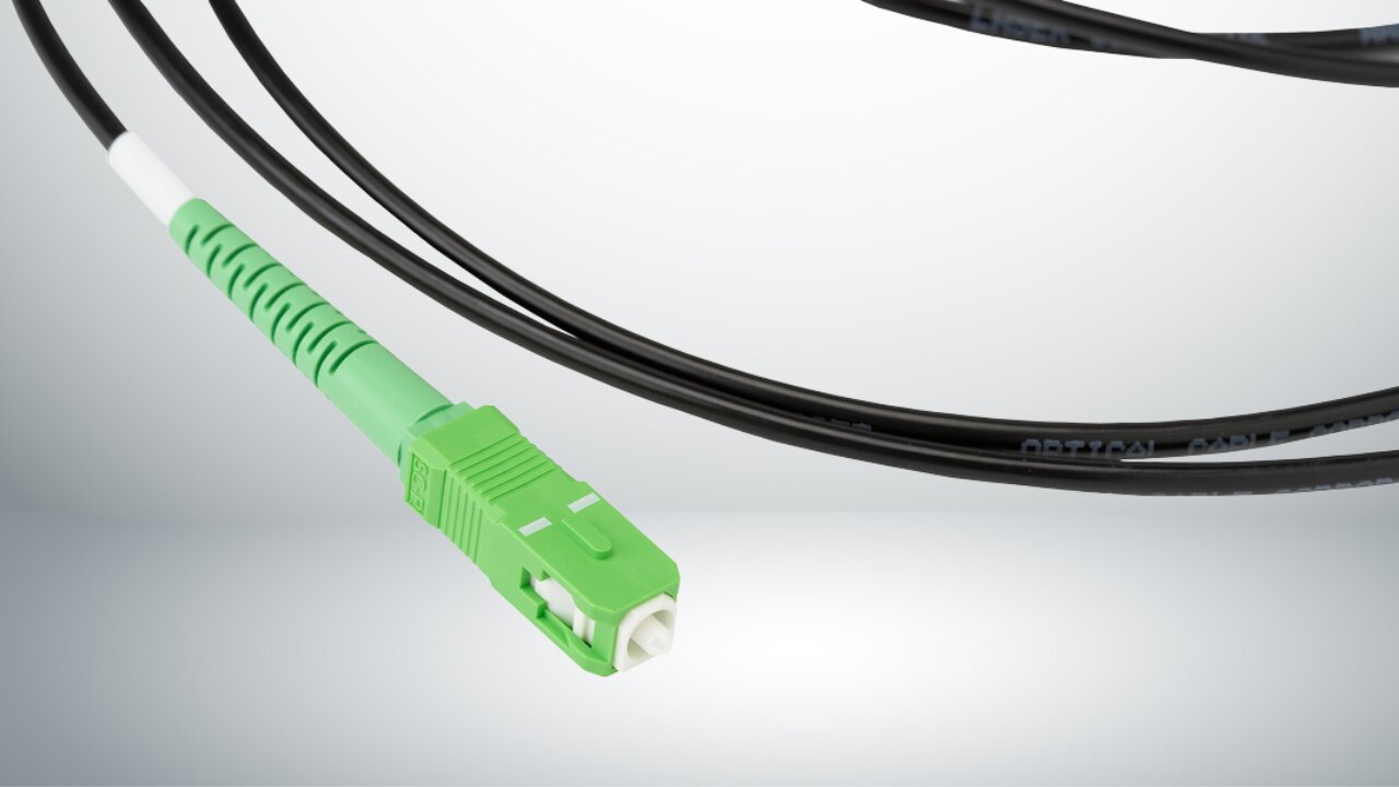 Green SC/APC fiber connector and coiled black fiber jumper cables.
