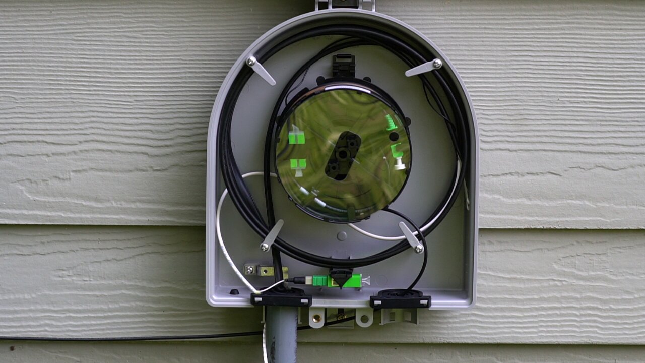 Open outdoor fiber terminal with coiled cable and green connectors.