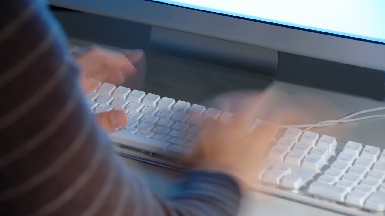 Person typing at a desktop computer.