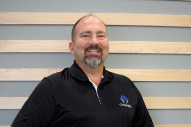 Portrait of a smiling man in a black polo shirt.
