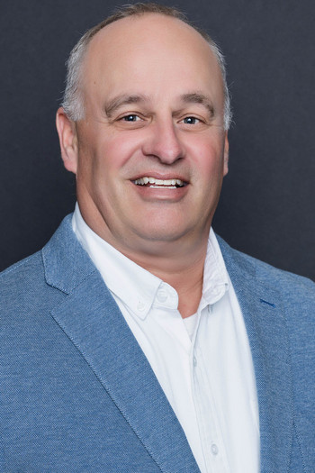 Headshot of a smiling man in a blue blazer.